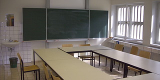 Schulraum mit Tafel und Klassenbänke