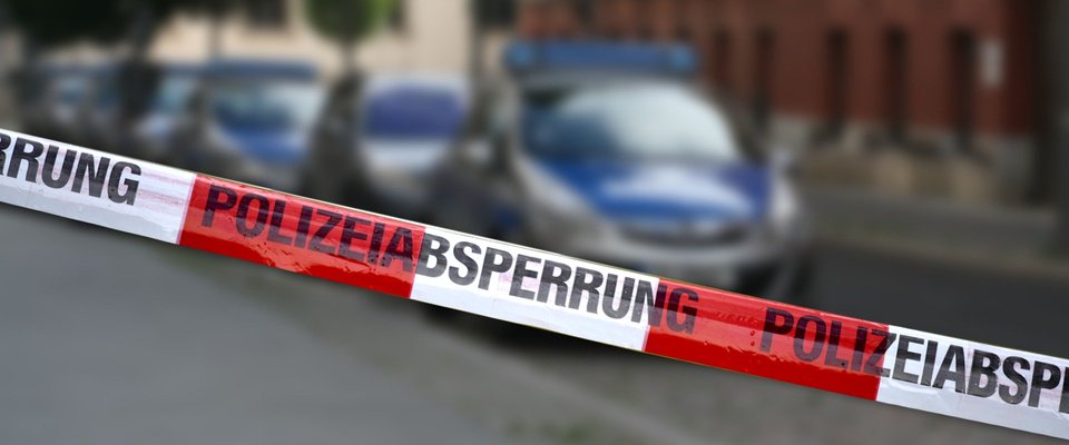 Polizeiautos vor Polizeiabsperrung.